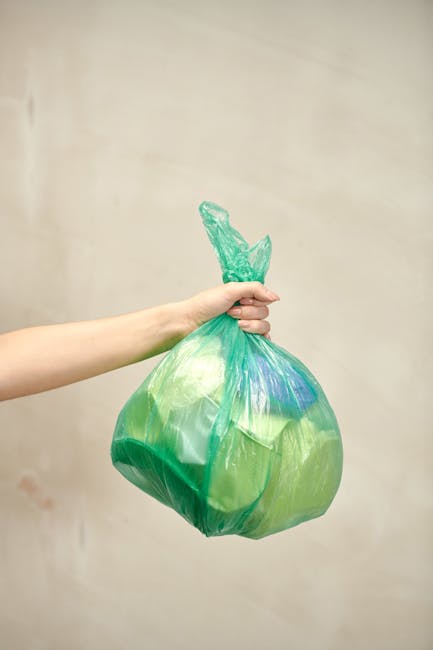Close-up of several black plastic rubbish bags filled with waste, stacked on top of each other inside a property near an open doorway, with some bags appearing full and tightly tied at the top. The setting suggests a home relocation or packing process as part of a house move, with the bags likely prepared for disposal or rubbish collection in accordance with Surbiton Council rules. The background includes a plain, light-colored wall and a portion of the doorway, indicating an indoor environment during the packing and moving stage. The scene reflects the final stages of packing materials, such as waste bags, before transporting or disposing of them, with the potential involvement of a professional removals service like Man with Van Surbiton.